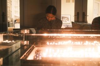 A young woman reads in front of an outdoor fire pit.