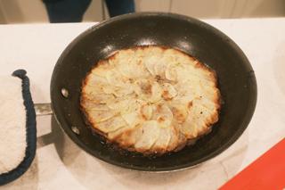 Pommes Anna cooking in a skillet.