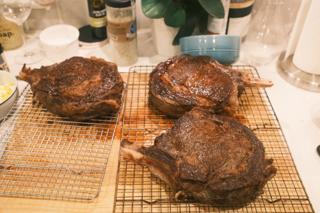 Three steaks resting on wire racks.