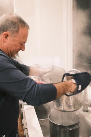 A column of rises as a man drains pasta into a kitchen sink.