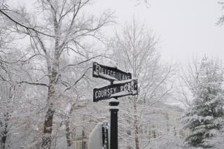 Snow covered intersecting road name markers.