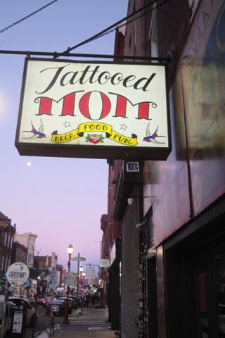 Lit-up sign for Tattooed Mom bar on South Street, Philadelphia.