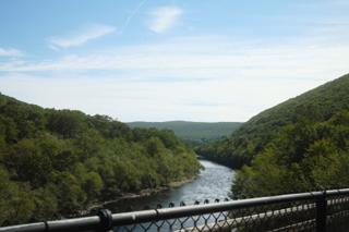 Part of the Lehigh River snaking between two green hills.