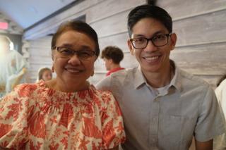 A mother and her grown son smile in a restaurant.