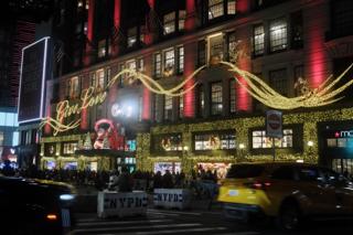 Holiday lights outside the Herald Square Macy’s in New York City, with “Give Love” in flowing script rendered with yellow lights.