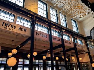 Interior windows of the Tin Building, under which runs a quote from Herman Melville’s Moby Dick: “There now is your insular city of the Manhattoes”