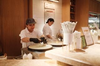 Two women make crepes.