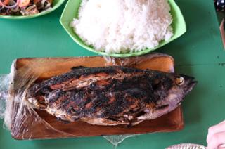 A grilled whole tuna fish on a wooden platter