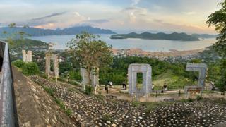 Islands in a bay in the background of a sign spelling out CORON