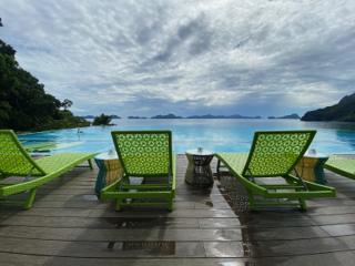 Two beach chairs on a deck, looking out on an infinity pool.