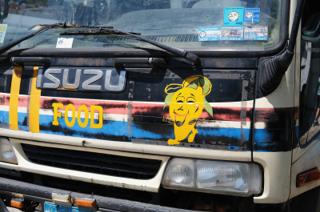 A truck painted with the word “Food” next to a smiling mango.
