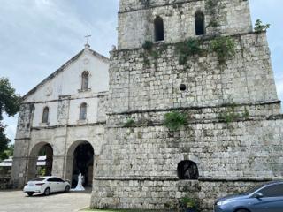 A bride stands just outside an old stone church.