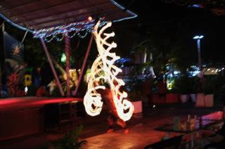 A man twirls fire, creating a pillar of fire several feet above his head.