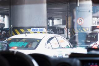 A taxicab with a roof sign saying “Brown Race”.