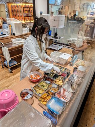 A woman assembles a bowl of instant ramen from a set of ingredients before her.