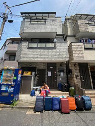 A row of colorful hard-sided rolling suitcases lined up outside an apartment building.