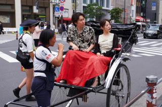 A man and a woman in a rickshaw chat with their driver.