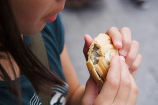 Closeup of a girl biting into an ice cream sandwich.