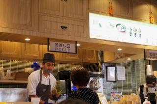 A man at a kitchen counter takes an order from a woman.