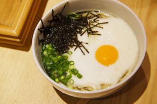 A bowl of udon topped with a fried egg, nori, and chopped green onion.