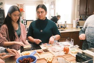 Two young women assemble a charcuterie spread.