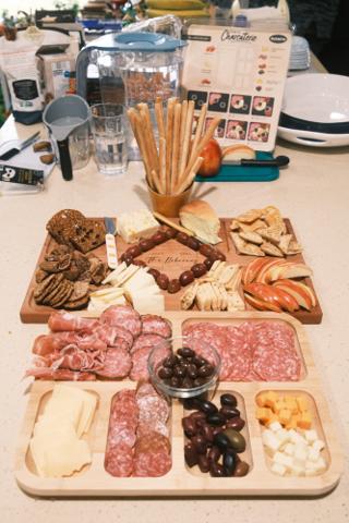 A charcuterie board with various meats, cheeses, olives, and sliced apples.