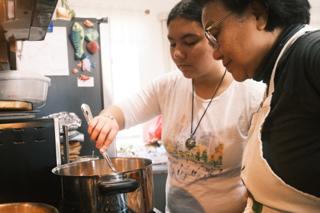 Two women deep-frying banana cue.