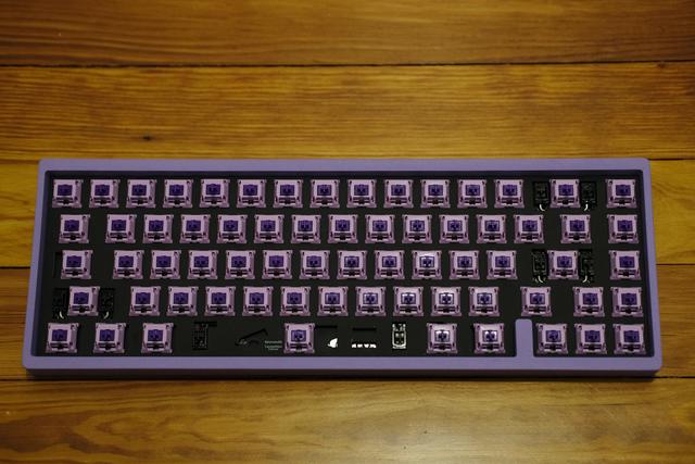 Top-down view of a keyboard with a lavender case, purple keyswitches, and no keycaps.