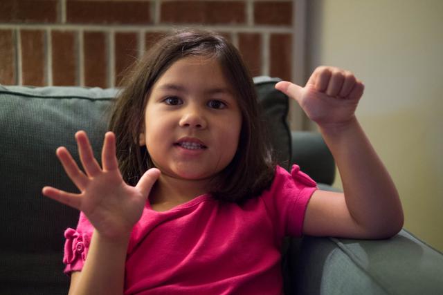 A girl holds up six digits on her two hands