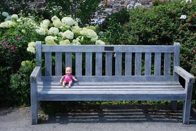 Doll sitting on a wooden bench.