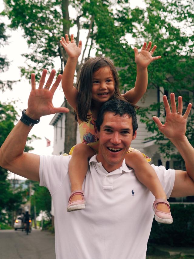 Young girl riding atop a man’s shoulders.