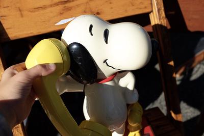 A Snoopy character phone, with the receiver held up to its ear.