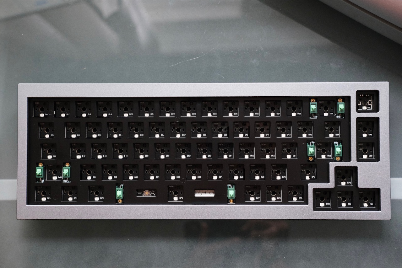 The bare board A top-down shot of a grey 65% keyboard with no keycaps or switches.