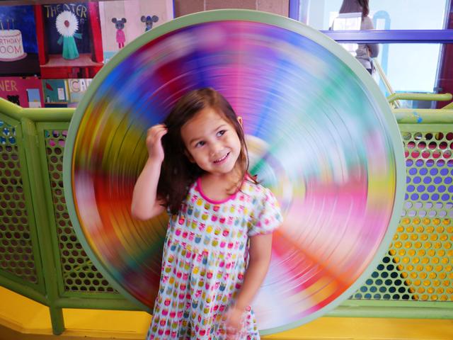 Color wheel blurred by motion behind a young girl.