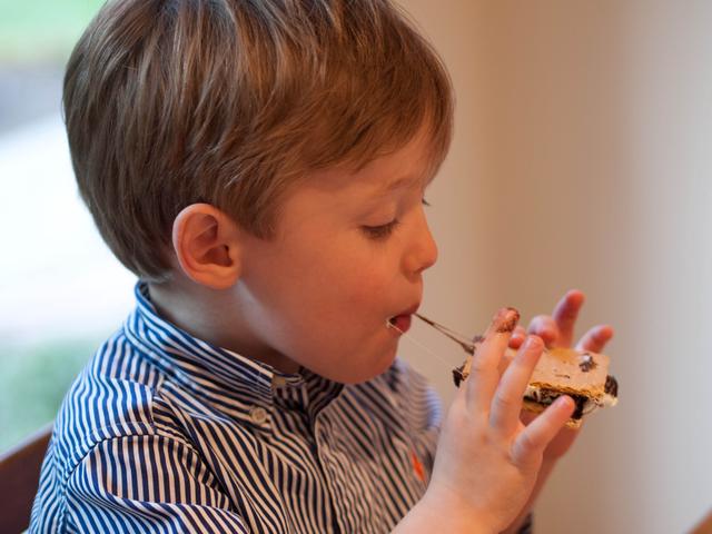A young boy eats a s’more.