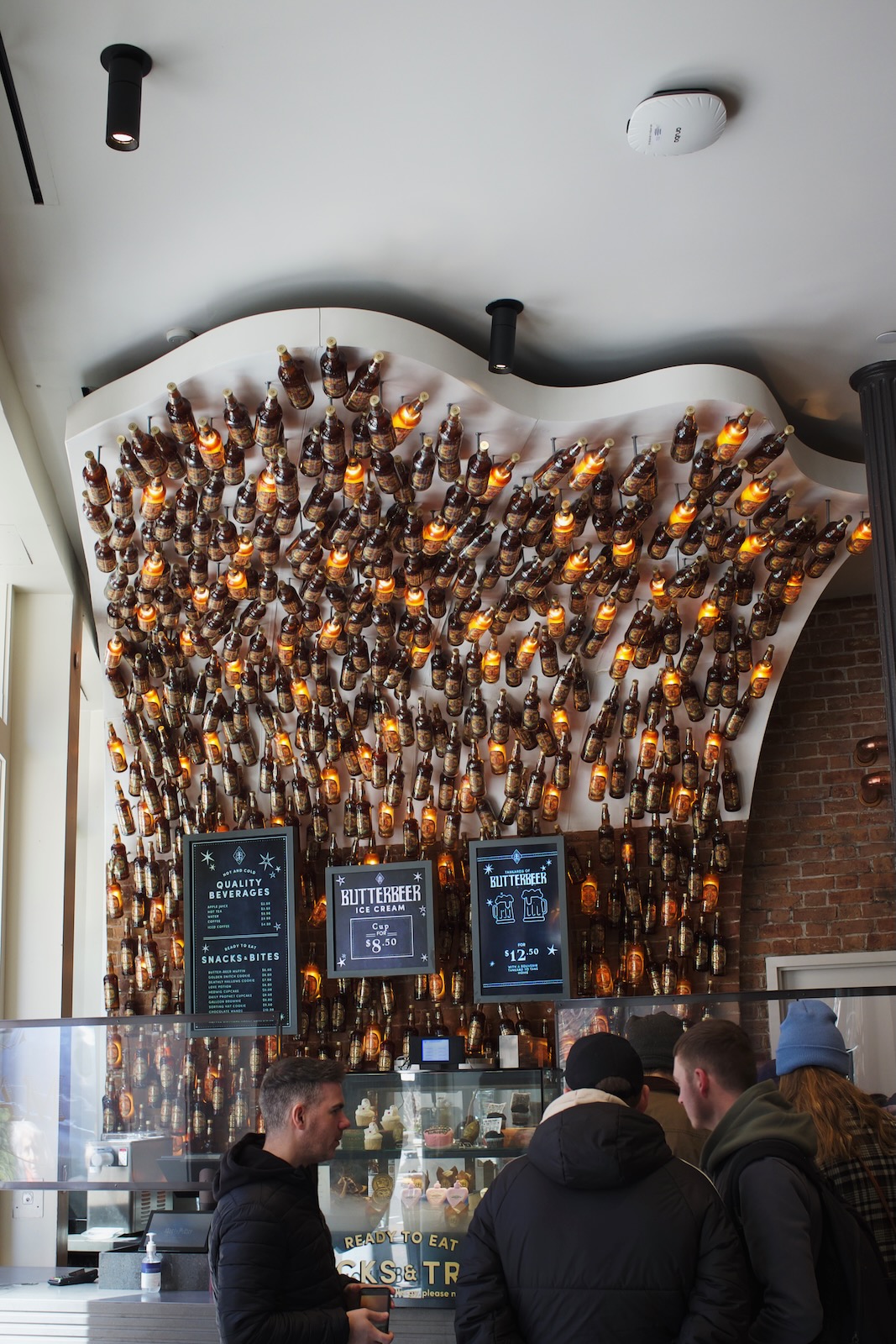 A bar with a back wall arching over top. The wall is decorated with dozens of bottles, some lit up by lights.