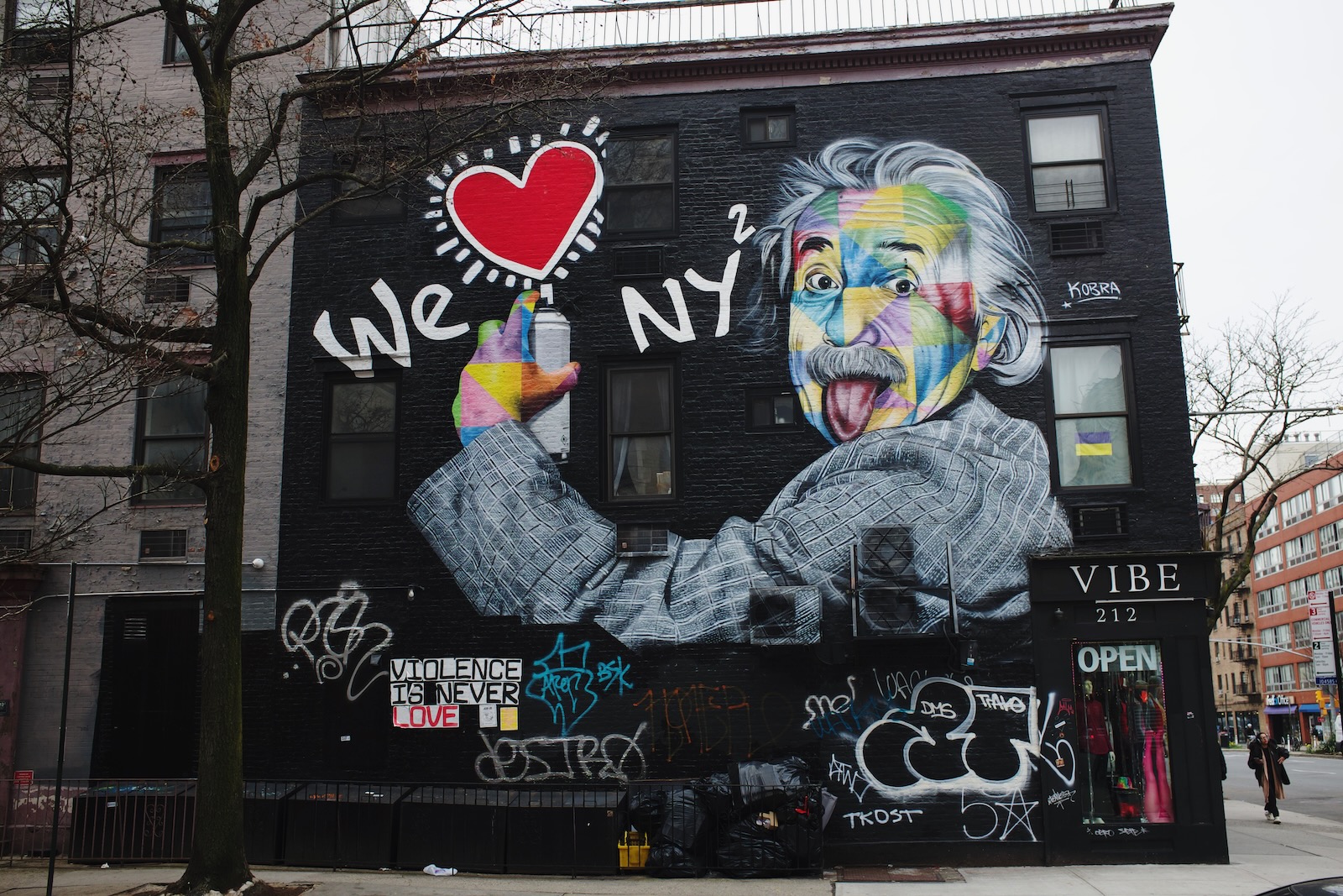 A mural on a black wall, with Albert Einstein portrayed spray-painting a message “We ❤️ NY.”