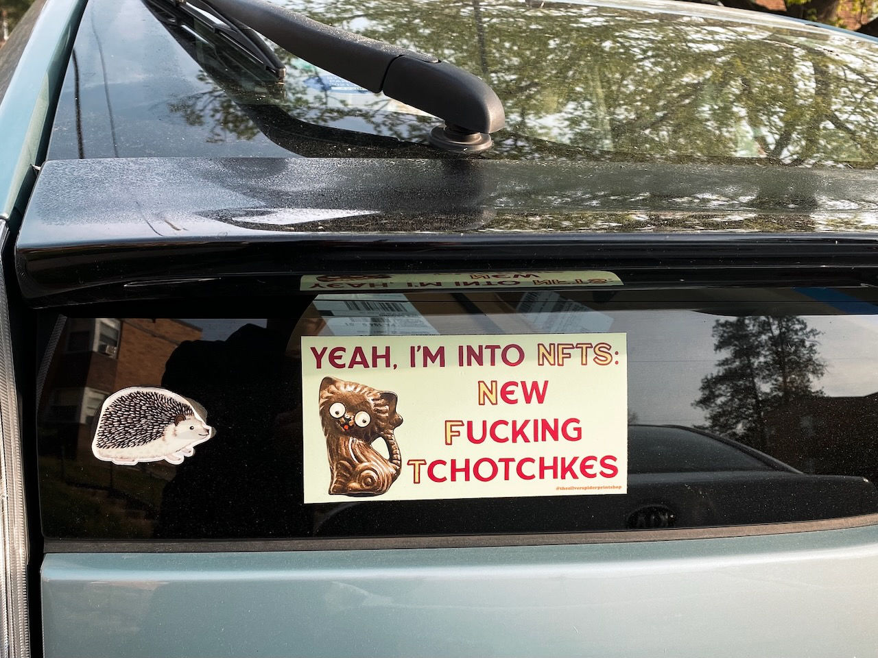 A bumper sticker reads “Yeah. I’m in to NFTs: New Fucking Tchotchkes”