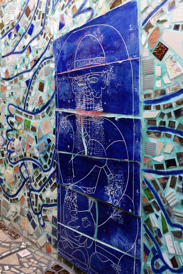 Drawing of a man set in 6 blue tiles stacked atop each other in a wall