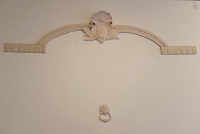 Sculpture mimicking a doorway with a doorknocker set in the wall.
