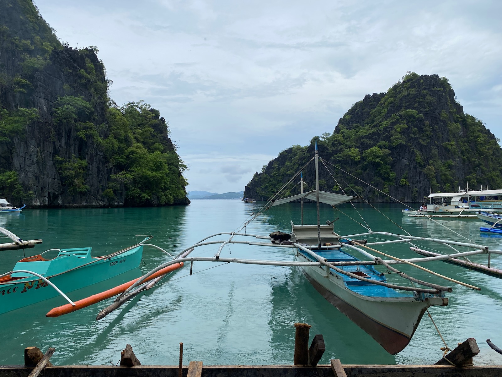 Bay leading to Kayangan Lake Outrigger boats tethered to a wooden walkway