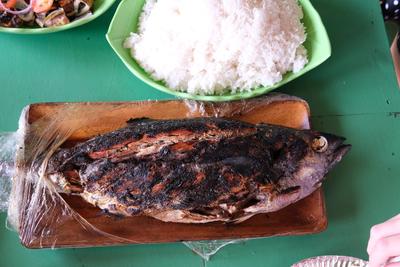 A grilled whole tuna fish on a wooden platter