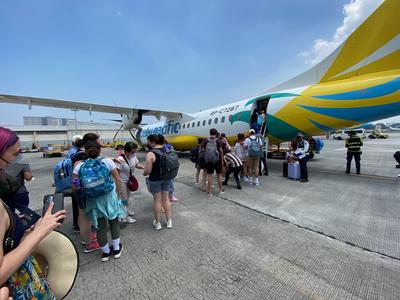 Passengers line up to board a small propeller plane.