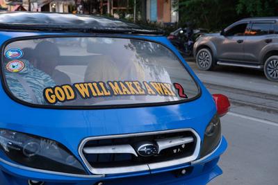 A tricycle emblazoned with the slogan “God Will Make a Way 2” on the windshield.