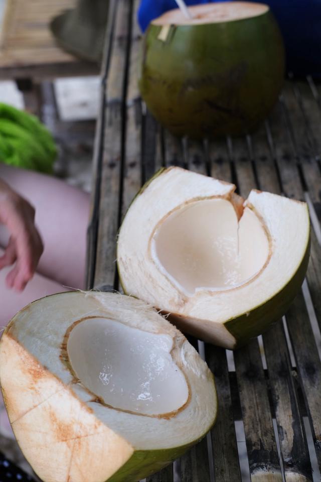 A woman sips from a young coconut.