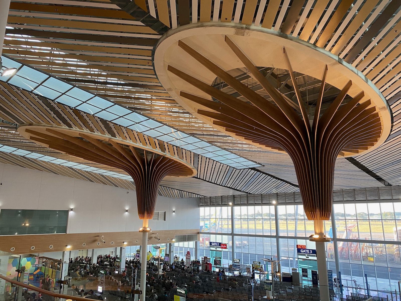 Puerto Princesa airport Two pillars with wooden decoration extend to an airport ceiling.