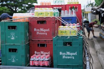 Flatbed truck loaded with crates full of San Miguel beer and soft drinks.