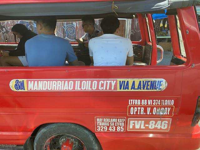 Side of a jeepney carrying a few passengers.