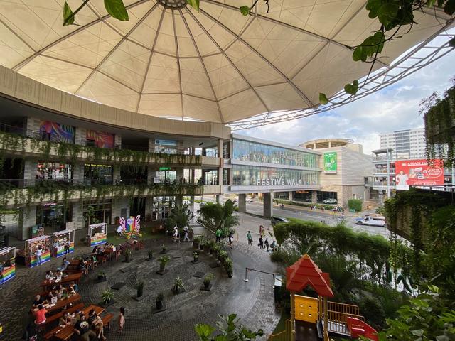 A massive canopy over an outdoor shopping mall patio. In the distance is an elevated crosswalk connecting it to another mall.