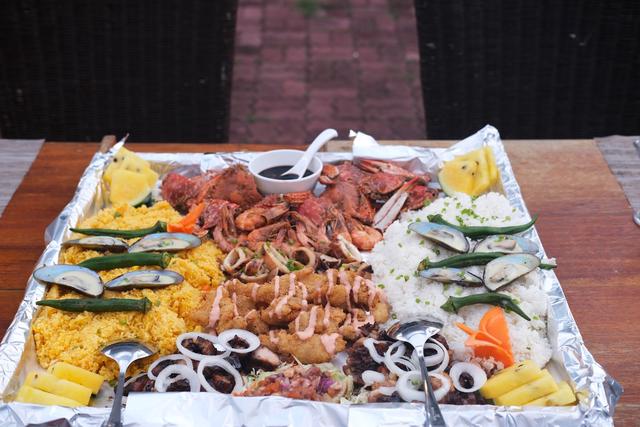 A boodle fight spread with shrimp, crabs, barbecued chicken, and fried rice